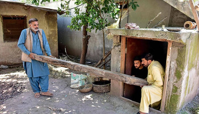 This photograph taken on April 28, 2025 shows Shabbir Awan (L) with his relatives clearing a wooden log from an underground bunker in the Chakothi village of Azad Kashmir, about 3kms from the Line of Control (LoC) — AFP