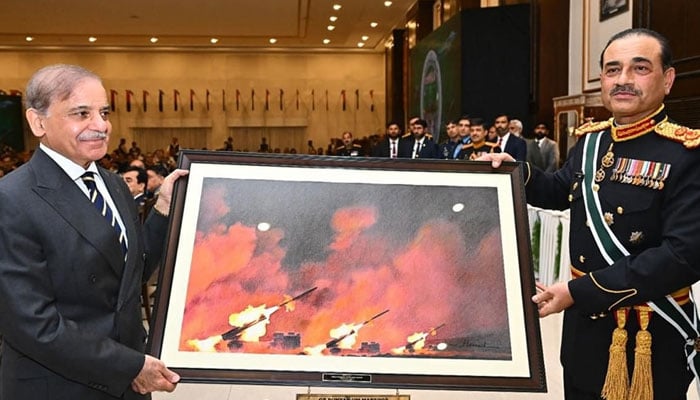 Prime Minister Shehbaz Sharif (left) presents a painting about war to Field Marshal Asim Munir. — ISPR