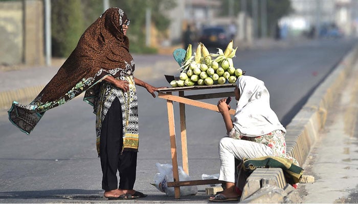 A woman sells roasted corn on a roadside inin Karachi on May 28, 2025. — INP